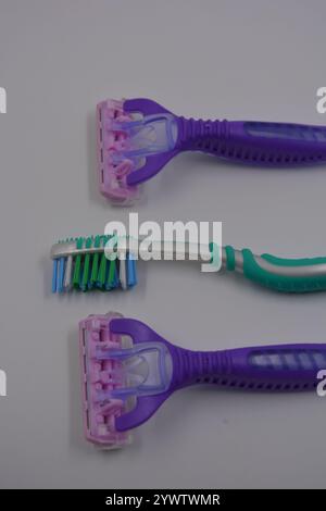 Women's things, things are made of plastic. Two women's purple machines for being armpits, a green women's toothbrush are arranged on a black plastic. Stock Photo