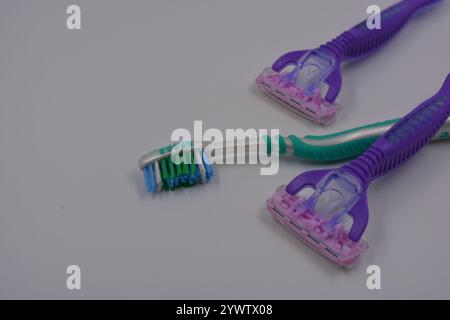 Women's things, things are made of plastic. Two women's purple machines for being armpits, a green women's toothbrush are arranged on a black plastic. Stock Photo