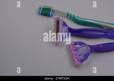 Women's things, things are made of plastic. Two women's purple machines for being armpits, a green women's toothbrush are arranged on a black plastic. Stock Photo