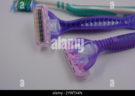 Women's things, things are made of plastic. Two women's purple machines for being armpits, a green women's toothbrush are arranged on a black plastic. Stock Photo