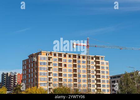 Сonstruction of a multi-storey residential building on a sunny day. Brick house under construction and tower crane against blue sky. Сonstruction site Stock Photo