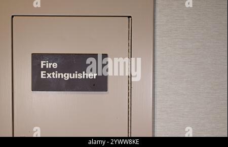 Fire extinguisher sign on hinged door in a wall Stock Photo