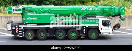 Green Emerson plant hire business heavy lifting high reach mobile crane telescopic jib above driver in cab at work driving on M25 motorway England UK Stock Photo