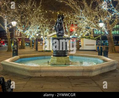 Deserted Sloane Square with it's Venus fountain in the centre with illuminated trees behind on a winter evening. London. UK Stock Photo