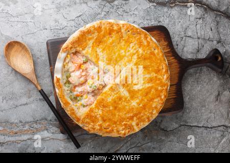 Festive fish Pot Pie with salmon, carrots, corn, onion and peas and in a buttery pie crust closeup on the baking dish on the table. Horizontal top vie Stock Photo