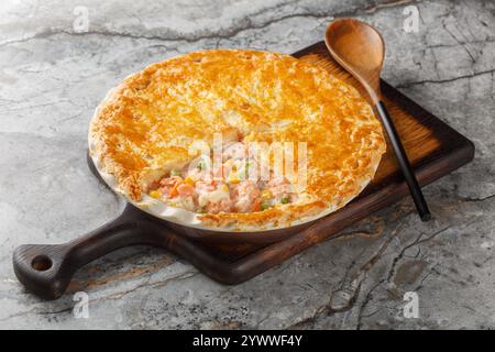 Festive fish Pot Pie with salmon, carrots, corn, onion and peas and in a buttery pie crust closeup on the baking dish on the table. Horizontal Stock Photo