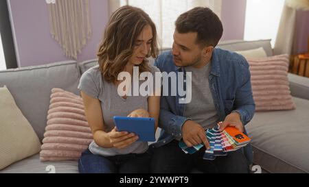 Couple looking at color samples for their home renovation, sitting on a couch in the living room, woman holding a tablet, man showing paint swatches, Stock Photo