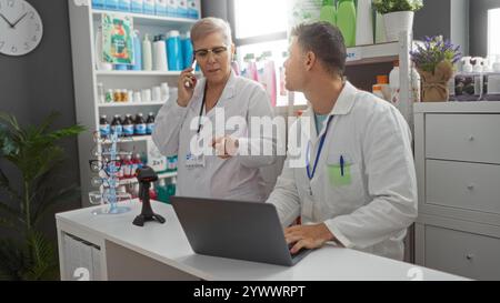Woman talking on phone and man using laptop in pharmacy with shelves of products and plants in the background Stock Photo