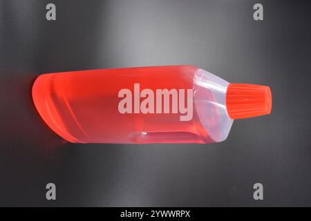 A large transparent bottle for washing clothes, bed linen, fabrics and cleaning rooms. A plastic bottle filled with a red liquid with a bright red cap Stock Photo