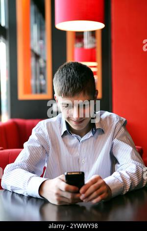 Cheerful Young Man Reading SMS on Mobile Phone at the Home Stock Photo