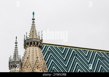 Vienna, Austria - May 12, 2019: Zigzag tile roof. View of top part of St. Stephen's Cathedral, Austria, closeup photo. St. Stephen's Cathedral is a Stock Photo