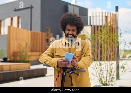 Smiling Man with Afro Hairstyle Using a Mobile Phone Outdoors Stock Photo