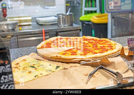 huge pizza with salami in a pizzeria cut into pieces Stock Photo