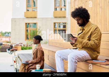 Man Using Tablet While Sitting on Wooden Bench Stock Photo