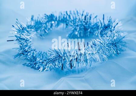 Silver Christmas glossy chain on background, copy space. Blue mnonochrome background. Stock Photo