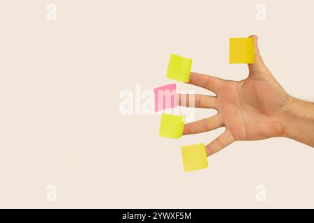 Blank colored sticky papers hanging on man fingers on a white background with copy space Stock Photo