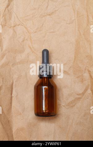 A brown bottle with a dropper on a wrinkled brown paper with copy space Stock Photo