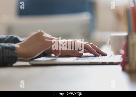 Close-Up of Hands Typing on Laptop Keyboard with Cup on Desk Stock Photo