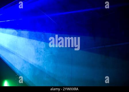 A blue and green light show with a blue wall. The blue light is on the left side of the image Stock Photo