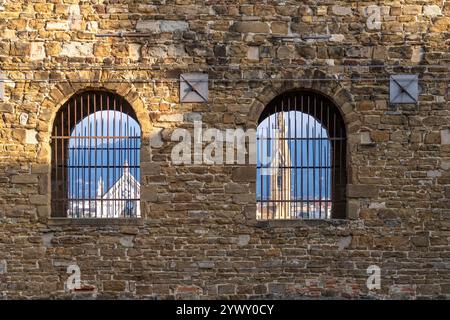 The Basilica of Santa Croce framed by the barred windows of the Palazzo Vecchio in Florence, Italy. Stock Photo