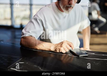 Cropped shot of mature man tapping phone screen text messaging on device placed on tabletop while spending time online at home, copy space Stock Photo
