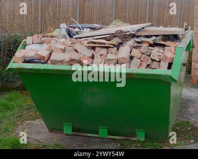 A dumpster or skip, full to overflowing with bricks and other building waste from a house renovation. Stock Photo