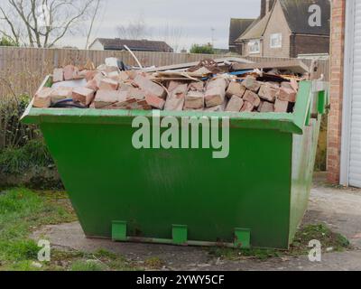 A dumpster or skip, full to overflowing with bricks and other building waste from a house renovation. Stock Photo