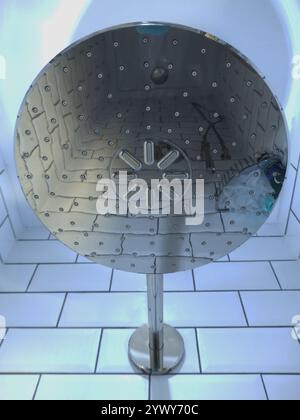 Closeup of the underside of a large modern shower head, which shows the reflections of other items below in a tiled shower cubicle enclosure. Stock Photo