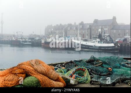 North Sea trawlers alongside on a foggy day in the deep sea fishing port of Peterhead which is situated in the north east of Scotland. Stock Photo