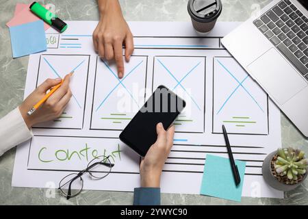 Developing UI design. Designers creating website wireframe on paper at grey marble table, top view Stock Photo