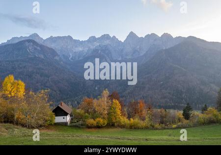 Drone scenery of charming house nestled amidst vibrant autumn foliage with the majestic Julian alps in the background. Slovenian landscape Slovenia Stock Photo