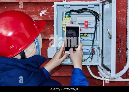 Electrical engineer takes readings of external electric meter in private house to submit electricity meter reading to energy company. Stock Photo