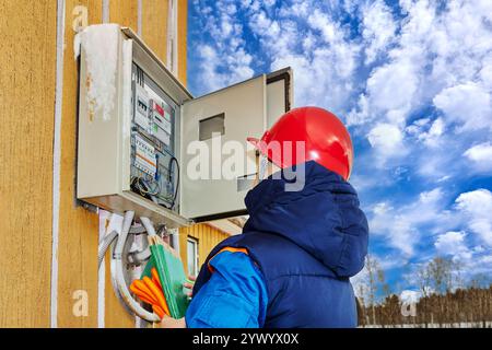 Technician of utility company checks reliability of connecting wires in an electrical panel. Stock Photo