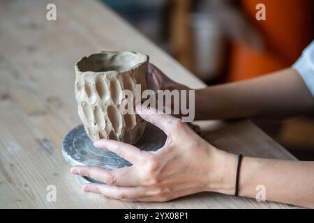 Woman potter hands carefully molding patterned vase or bowl in pottery studio. Textured sculpting Stock Photo