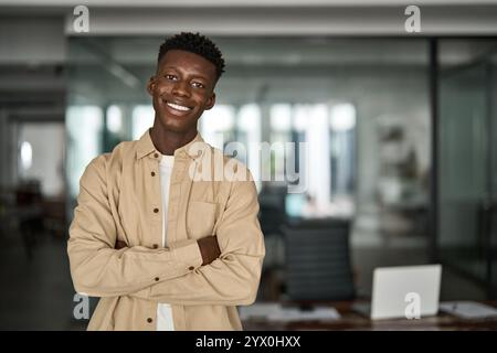 Portrait of young happy Black business man looking at camera standing in office. Stock Photo