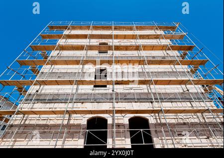 old building during reconstruction with wooden scaffolding viewed from below Stock Photo