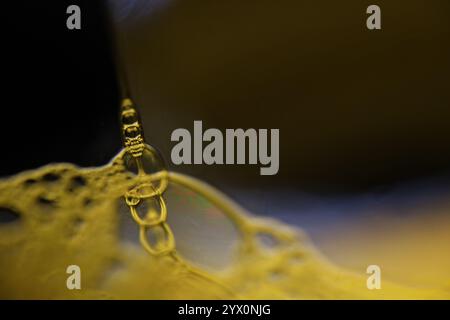 Yellow liquid reflections on black background, fluid abstraction, colour waves, deep dark backgrounds, smooth motion Stock Photo