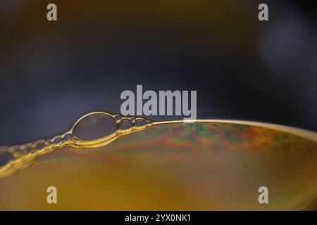 Yellow liquid reflections on black background, fluid abstraction, colour waves, deep dark backgrounds, smooth motion Stock Photo
