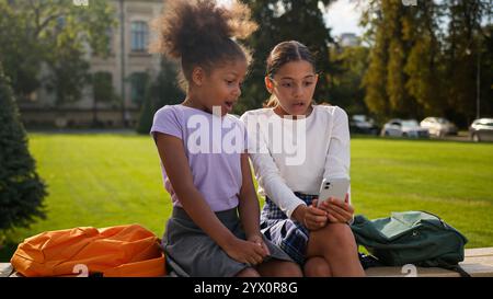 Little kids girls female children friends multiracial ethnic sisters African American Indian schoolgirls pupils elementary students gadget addict Stock Photo