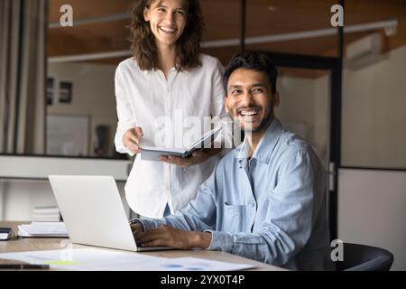 Two joyful Hispanic and Indian teammates working on joint task Stock Photo