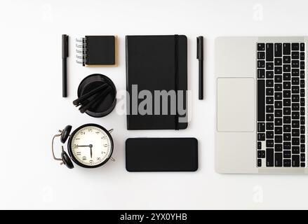 Trendy arrangement made with computer, notebooks, pens, alarm clock and phone on white background. Minimal business concept. Creative office objects... Stock Photo