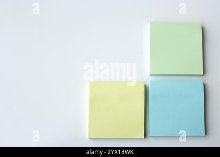Three square pastel color sticky notes on white background with copy space. Creative stationery for study, brainstorm, office meetings and school Stock Photo
