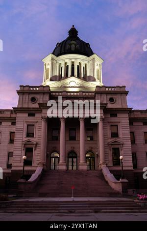 View looking up the steps of the South Dakota state capitol building in Pierre at sunset with a pink sky beyond Stock Photo