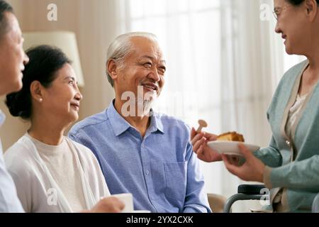 group of happy senior asian gathering at home having a nice chat Stock Photo