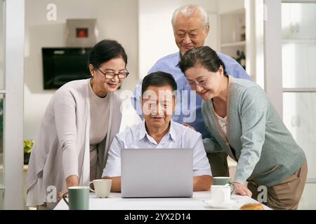 two happy asian couples using laptop computer together at home Stock Photo