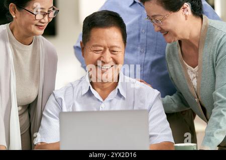 two happy asian couples using laptop computer together at home Stock Photo