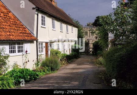 Old Guildhall, now terrace cottages, and St Mary and St Clement Church along lane in Clavering, Saffron Walden, Essex, England, UK Stock Photo