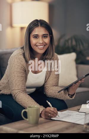 Home, woman and tablet in portrait for budget, track expenses and planning for finance goal on sofa. House, happy person and writing on statement for Stock Photo