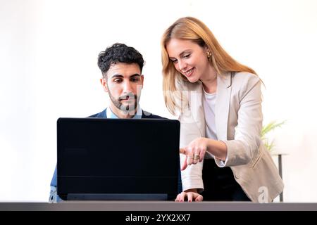 Colleagues Collaborating on Laptop in Bright Office Setting Stock Photo