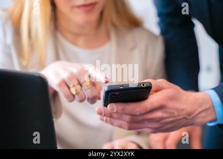 Unrecognizable colleagues discussing work while using a smartphone in the office Stock Photo